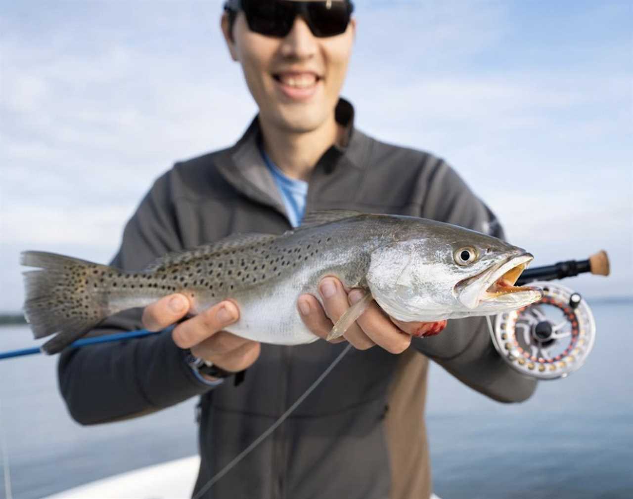 A man in black sunglasses holding a fish