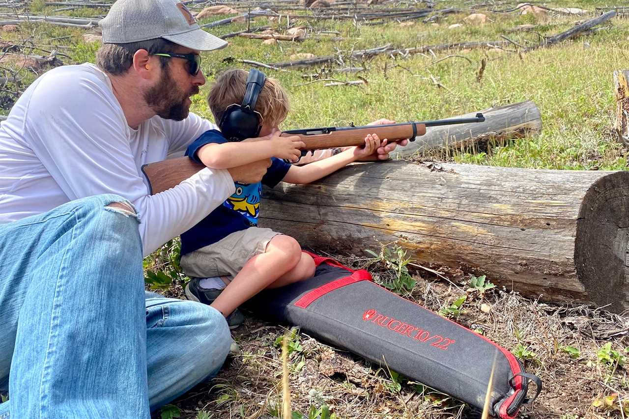 man teaches child to shoot