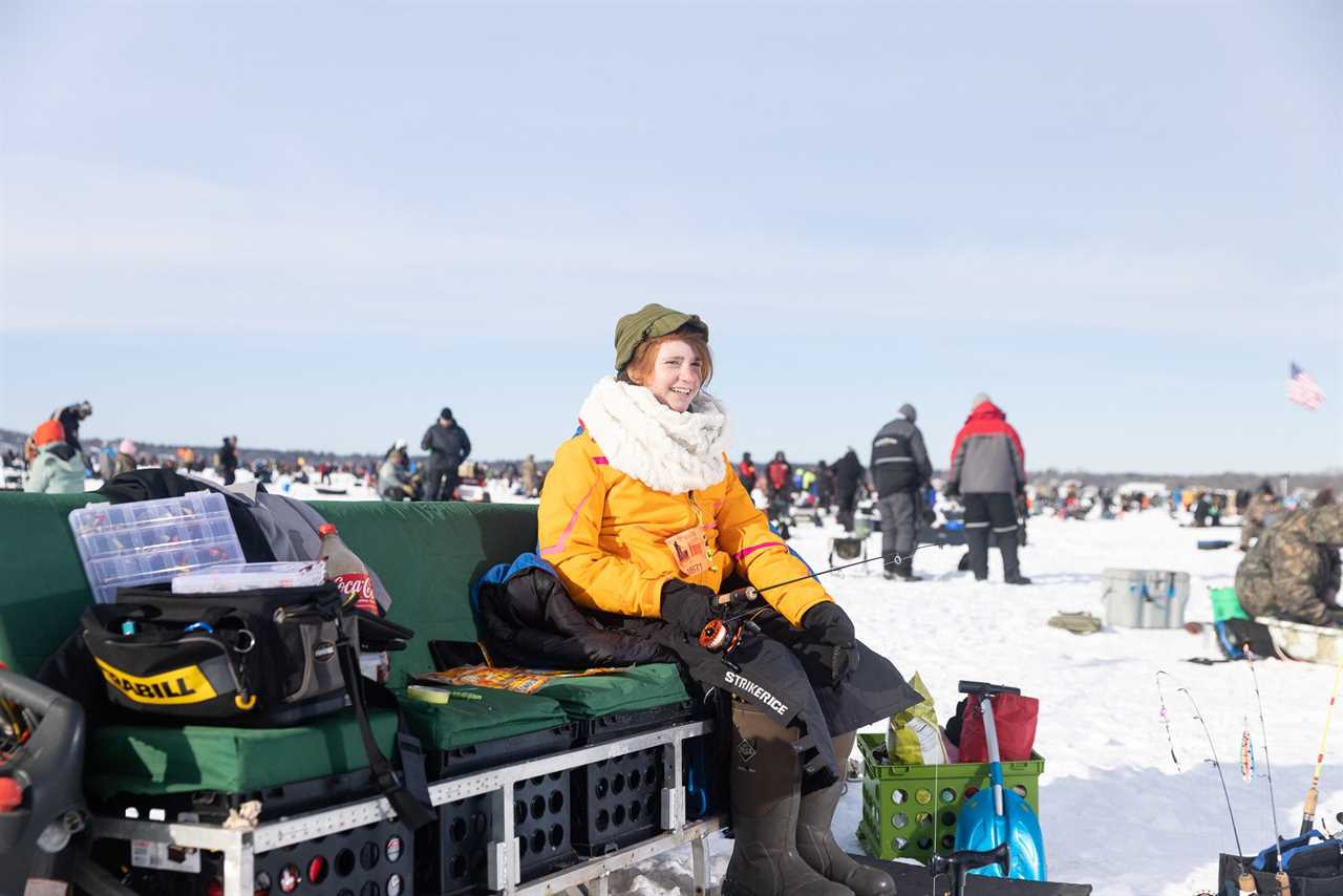 A red haired girl in a yellow coat fishes.