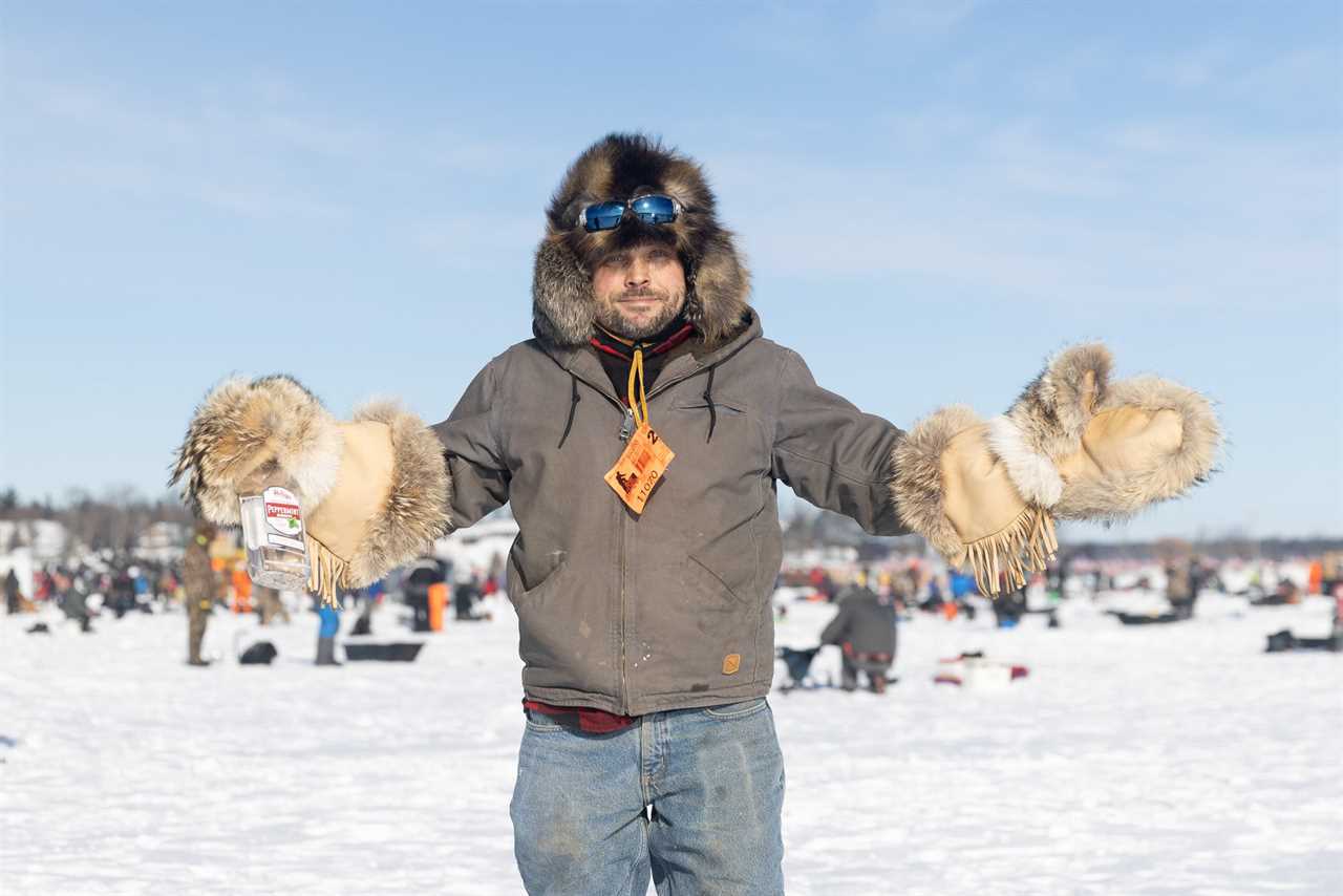 A man in fur holds out a bottle of peppermint schnapps.