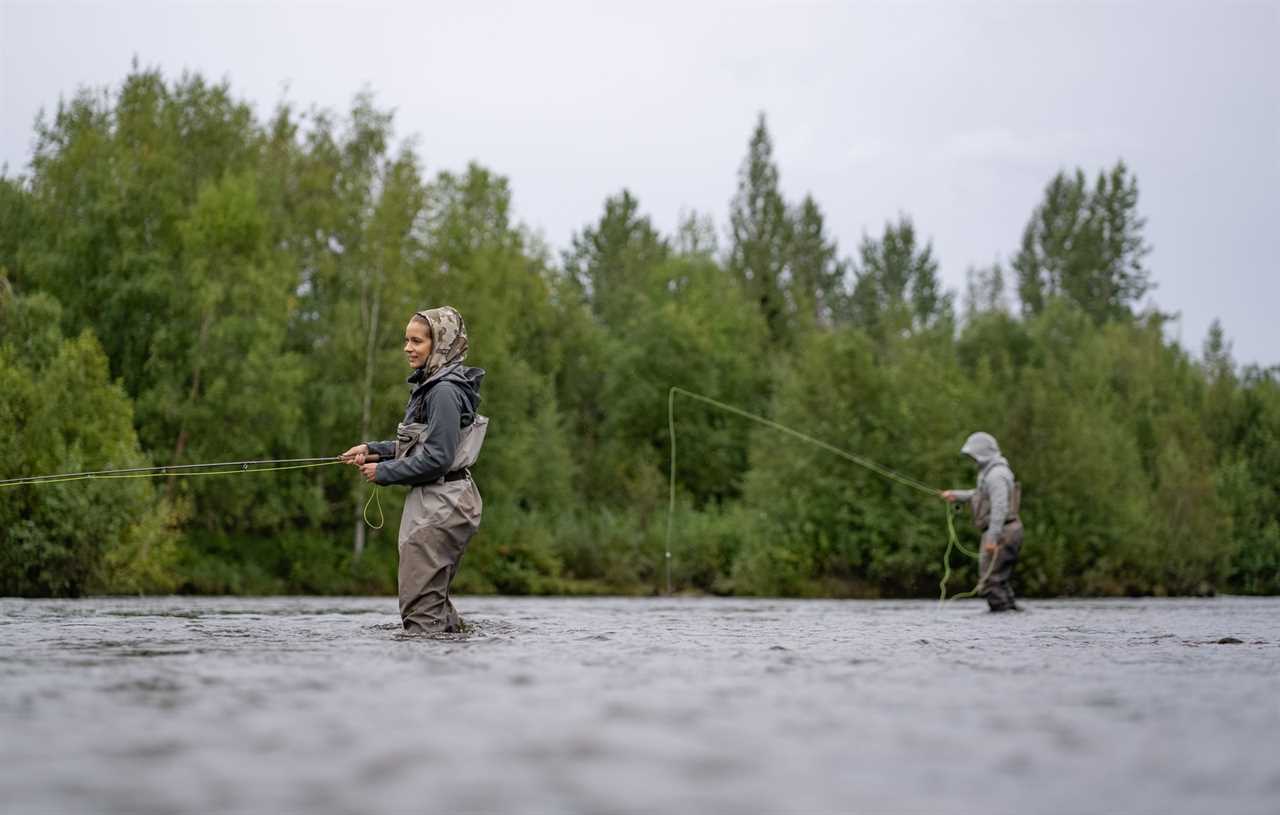 A man and a woman in fishing waders fly fish Willow Creek in Alaska.