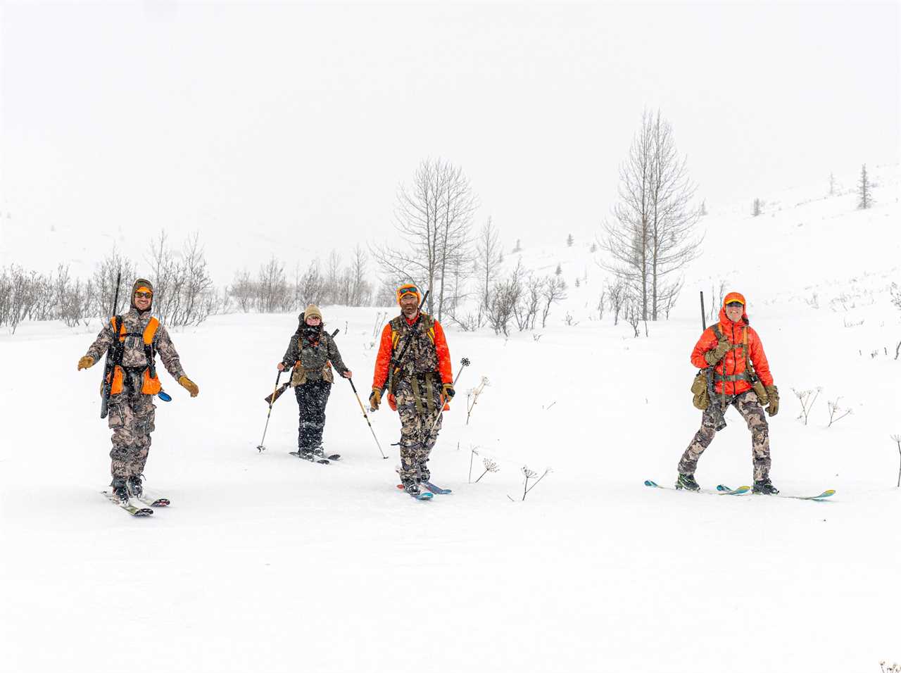 Four bird hunters skiing in the snow.