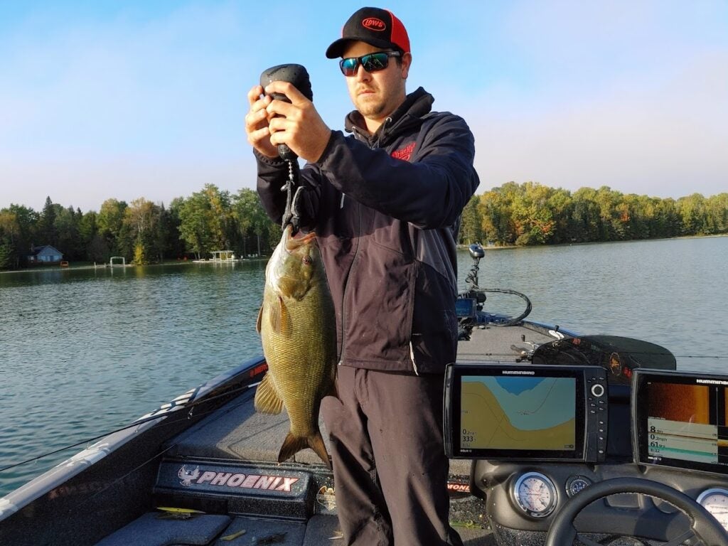 A man on a boat weighing a fish on a scale