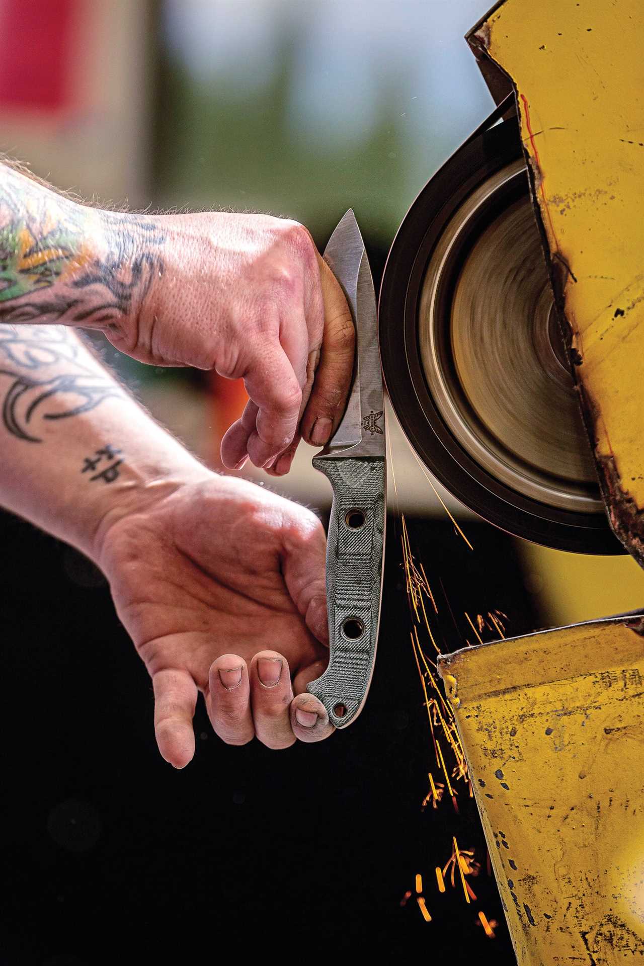 A Benchmade knifemaker grinds a knife.