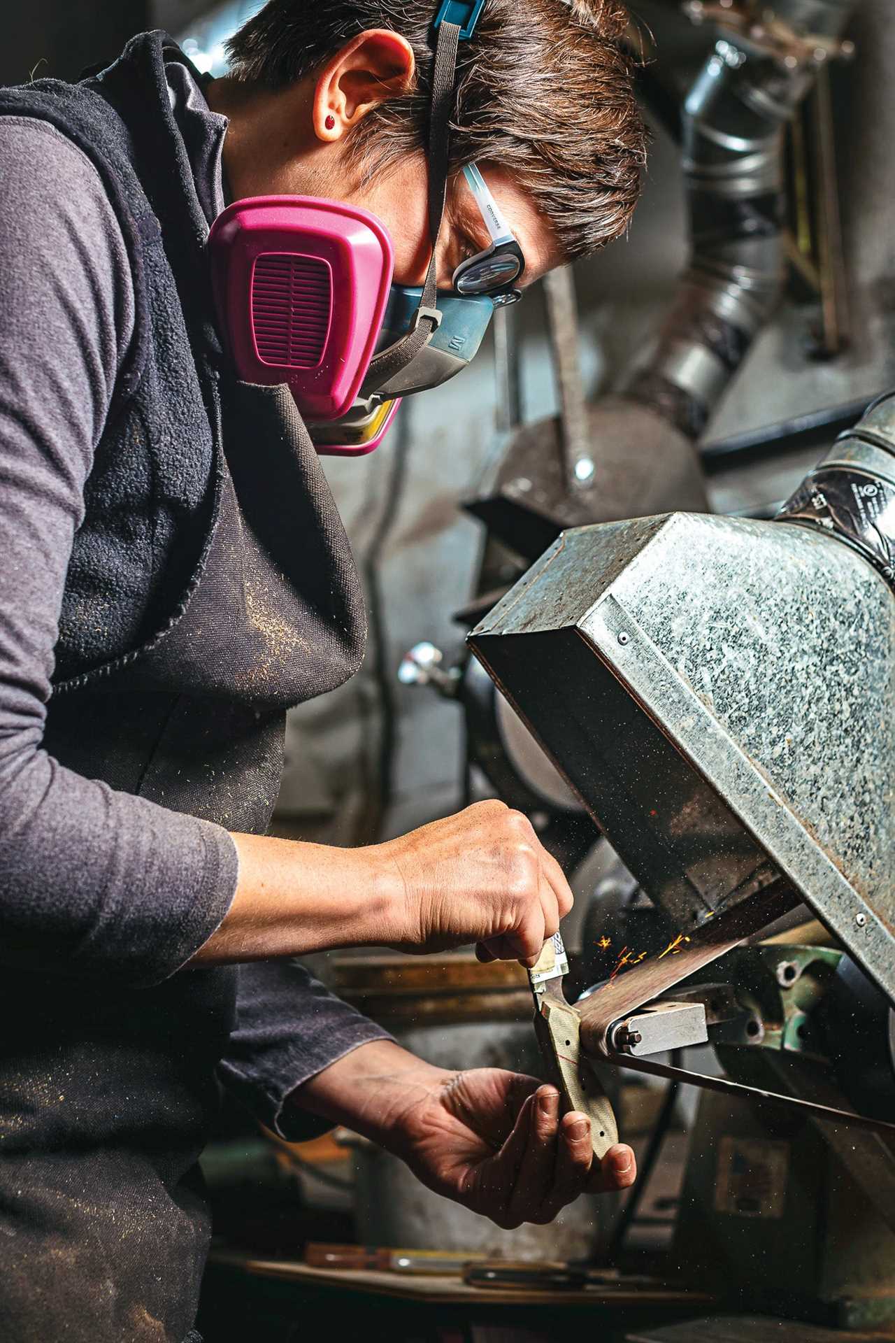 A woman contours a knife handle in a Portland workshop.