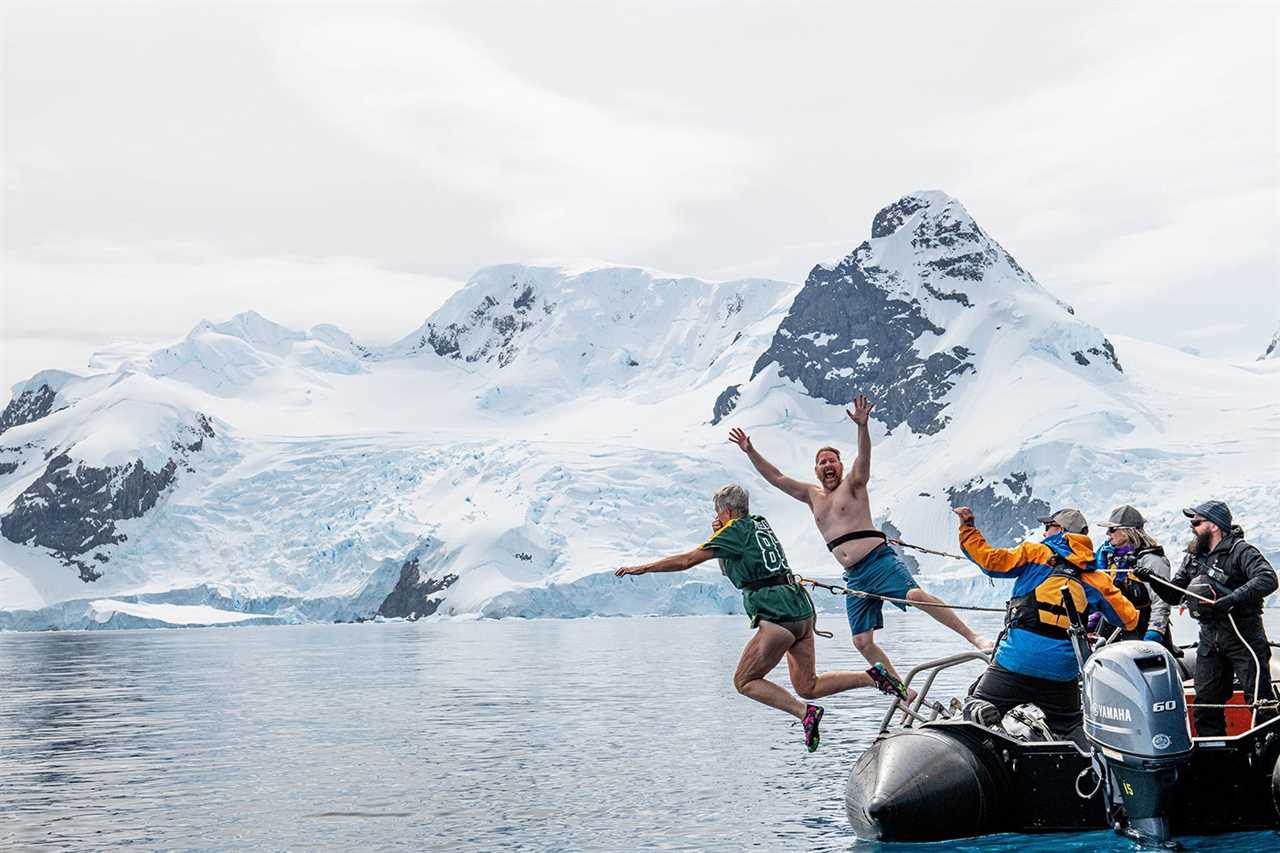 two tourists leap from a boat into the antarctic water