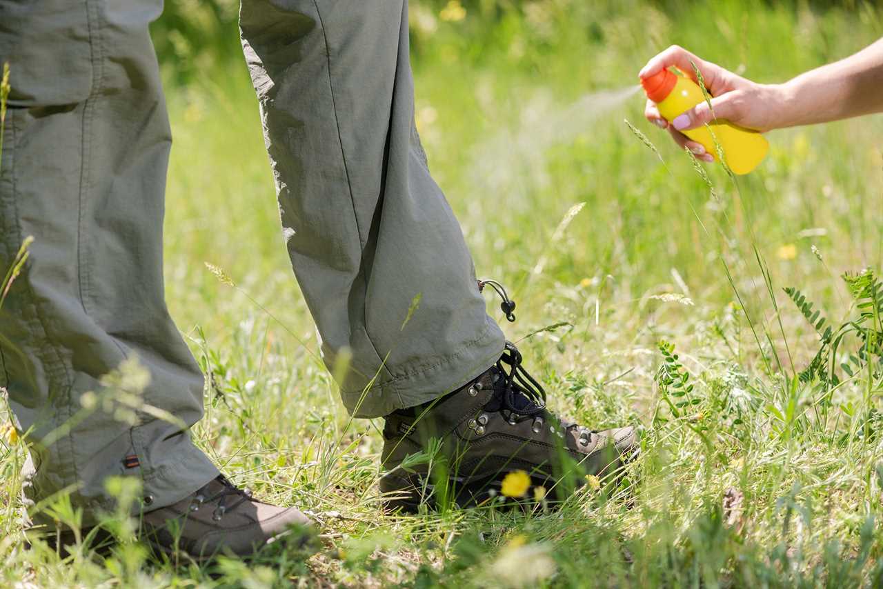 Spraying insect repellent on hiking pants.