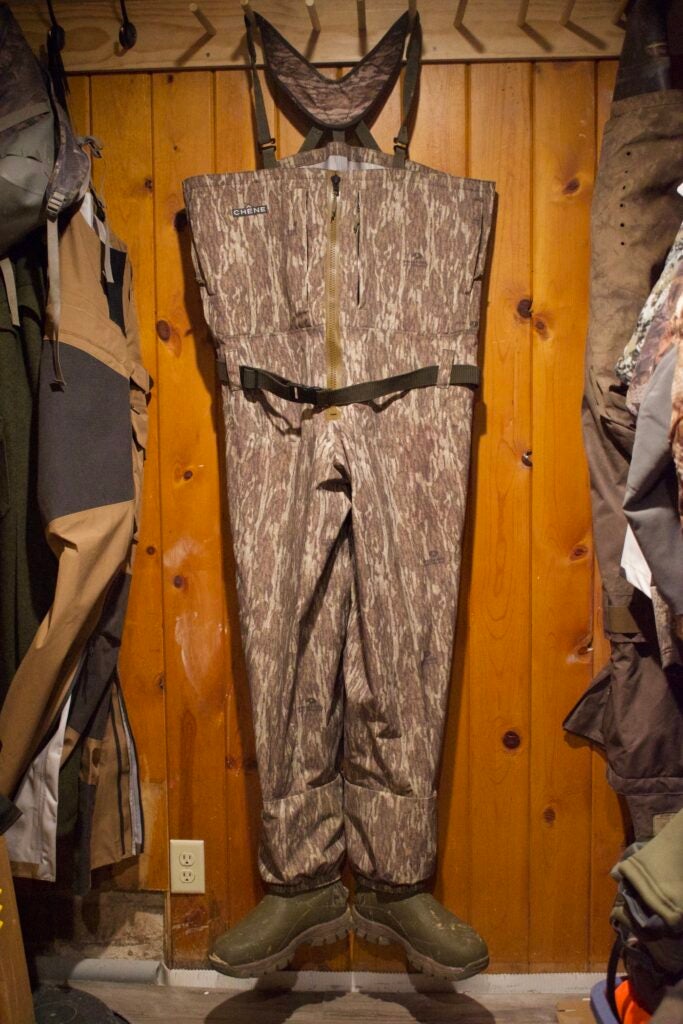 Brown waders hanging against a wood wall