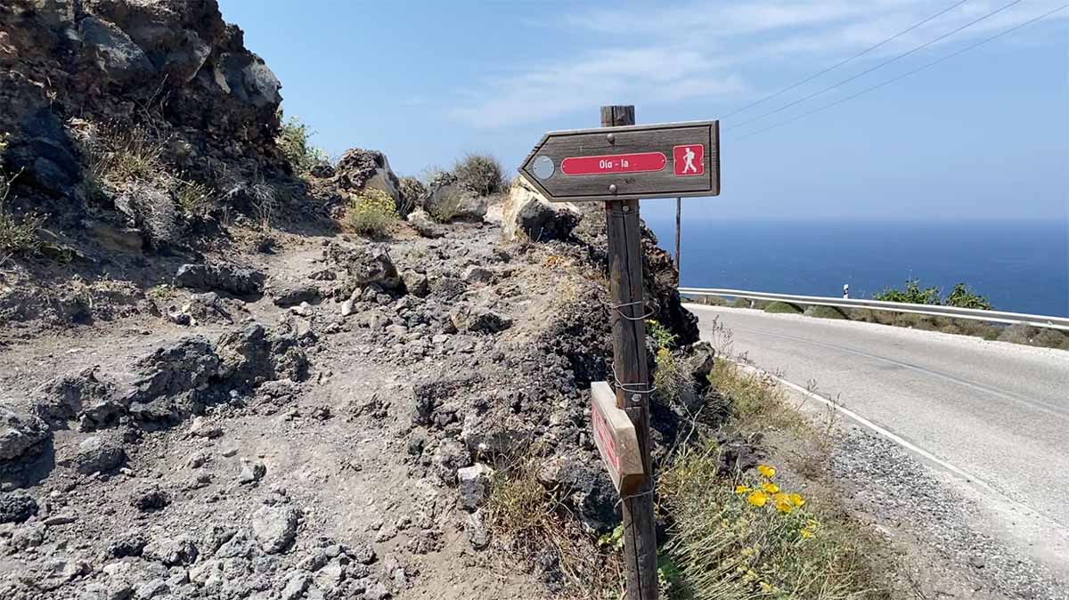 The rocky Fira to Oia hiking trail with a sign pointing left