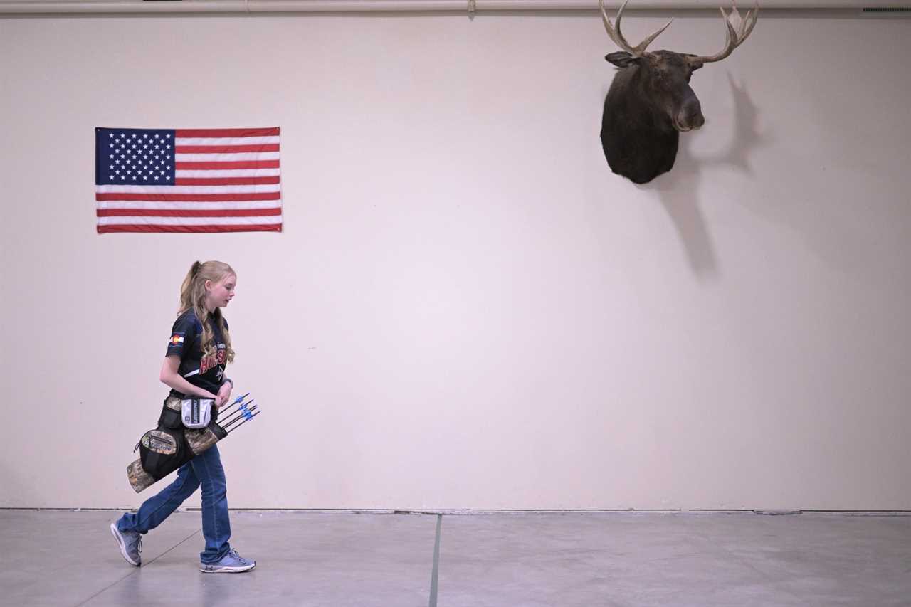 A teenage archer walks downrange to pull her arrows.