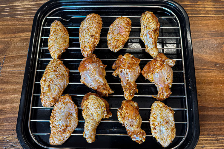 raw seasoned chicken wings on a wire rack