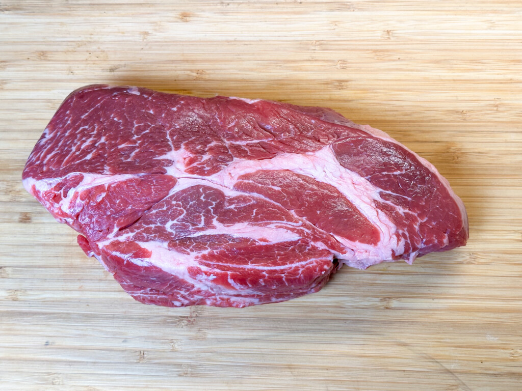 raw chuck roast on a wooden chopping board