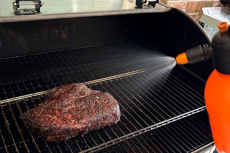 spritzing a chuck roast on the smoker