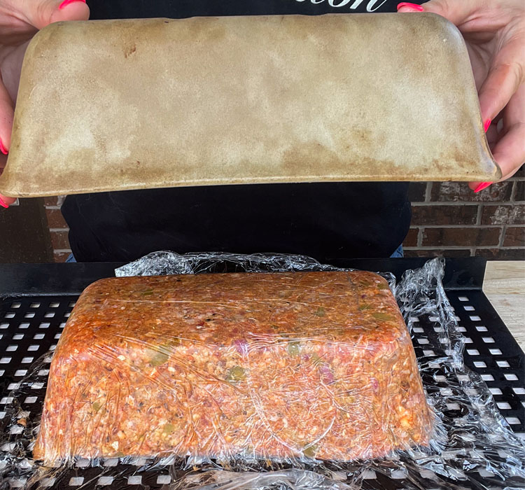 removing the loaf pan from the uncooked meatloaf