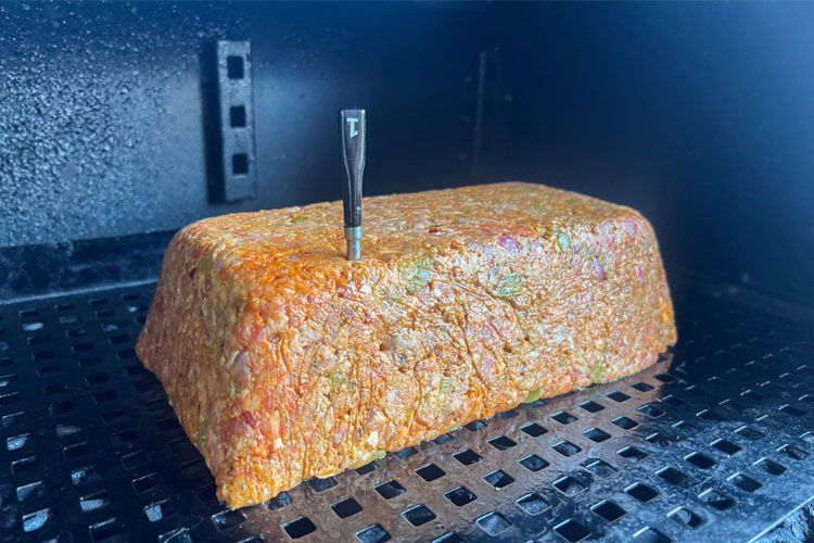 raw meatloaf in the smoker with a temperture probe