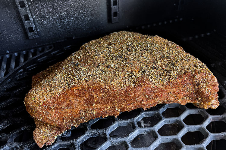 raw seasoned dino rib on the smoker