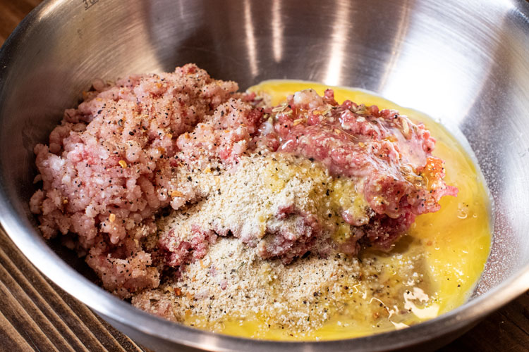 raw ingredients of meatballs in a metal bowl