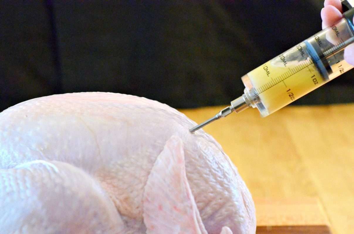 Injecting a raw turkey with marinade