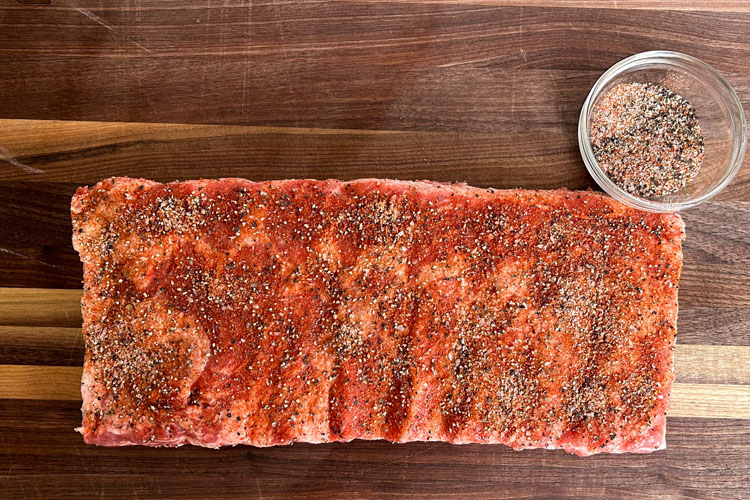 raw seasoned wester carolina ribs on a wooden chopping board