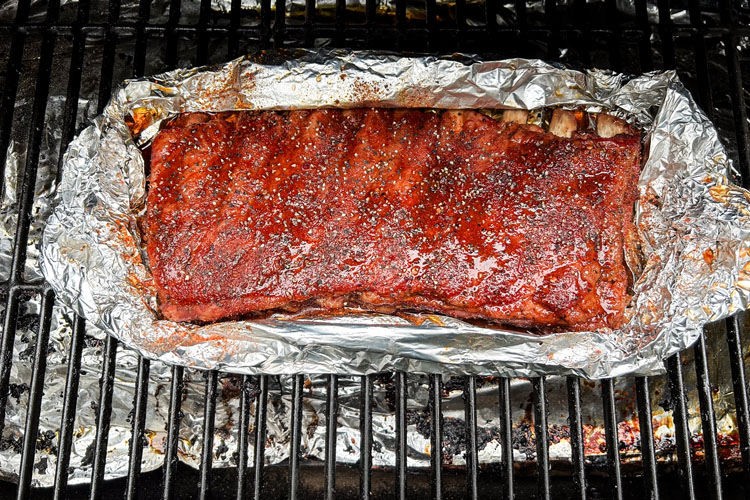 western carolina ribs sitting on foil in the smoker