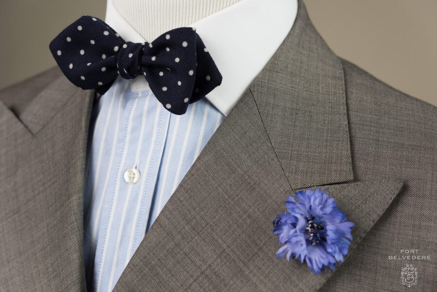 Pale blue and white Winchester shirt paired with a navy bow tie and blue cornflower boutonniere