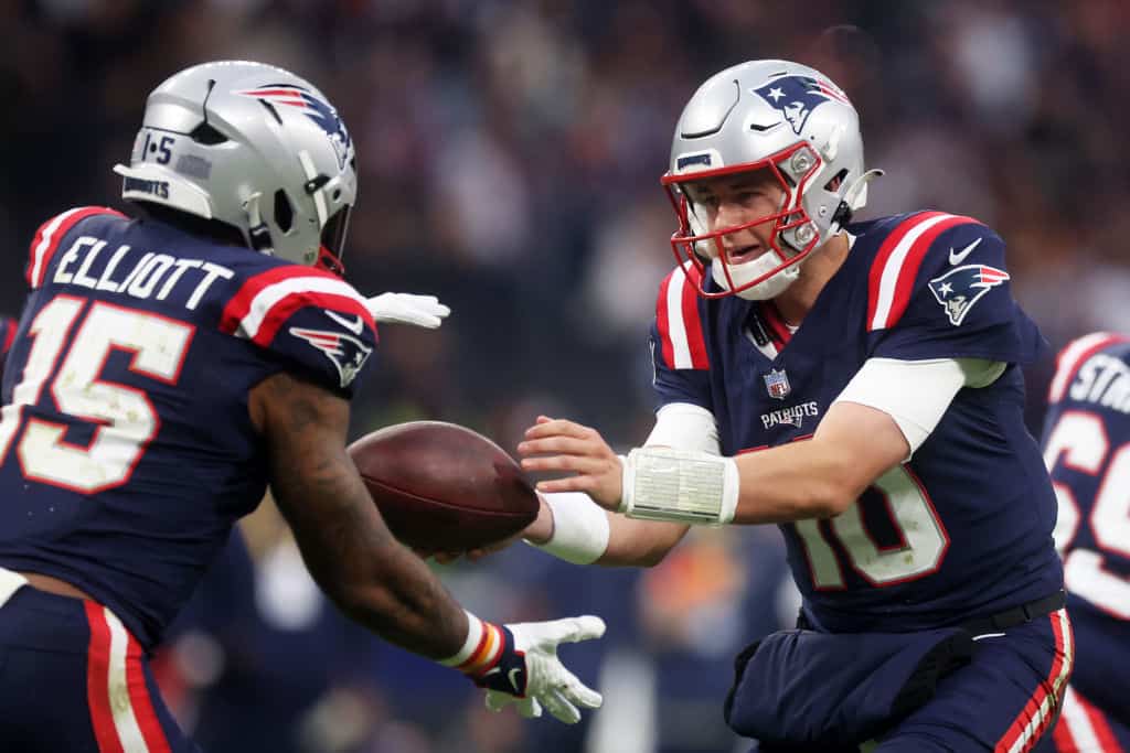 Mac Jones #10 of the New England Patriots hands off to Ezekiel Elliott #15 of the New England Patriots in the second quarter during the NFL match between the Indianapolis Colts and the New England Patriots at Deutsche Bank Park on November 12, 2023 in Frankfurt am Main, Germany.