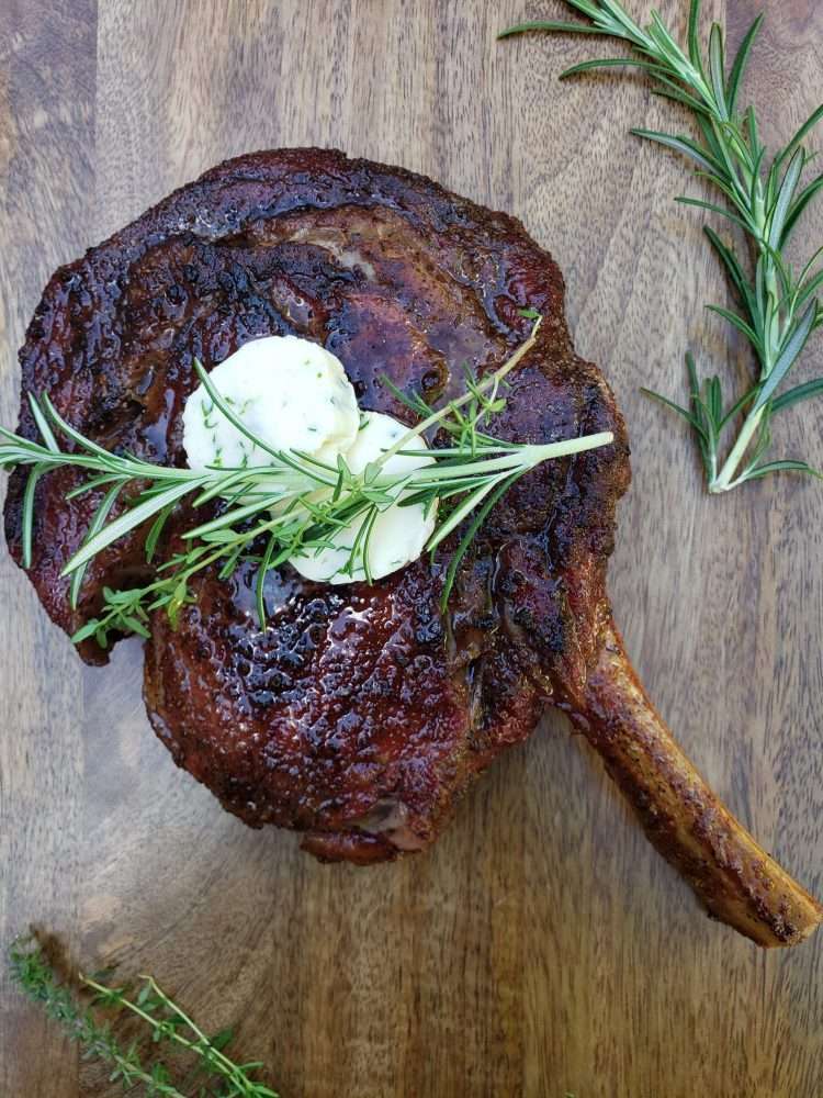 Grilled cowboy steak with rosemary sprigs and butter