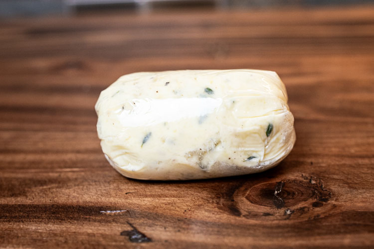 a log of compound butter on a wooden board