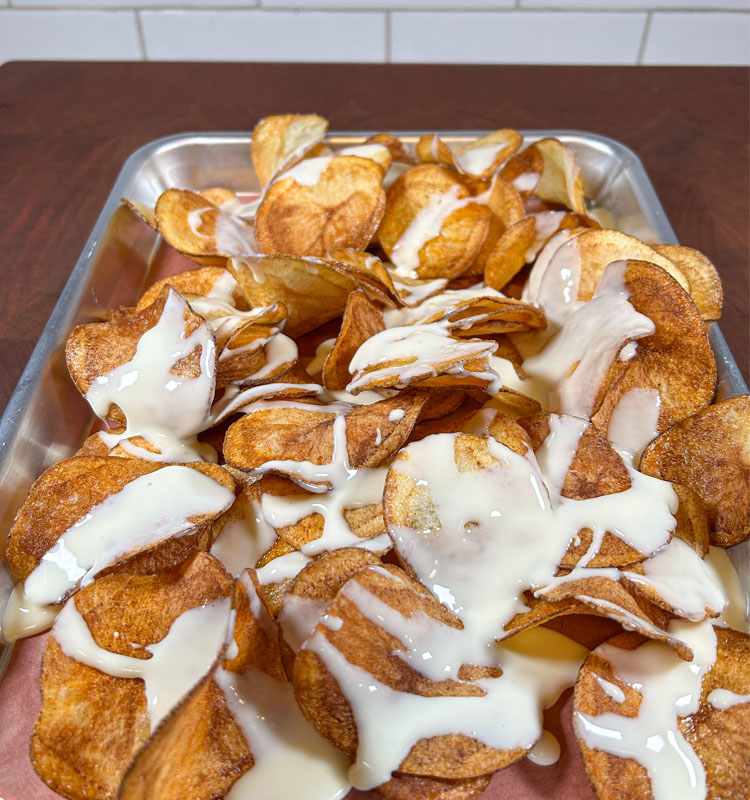 chips in a metal tray drizzled with queso