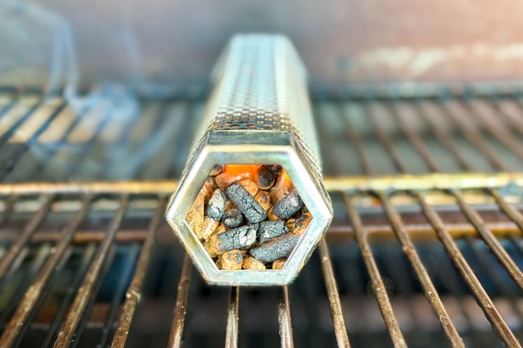 smoke tube with lit pellets inside on the grill