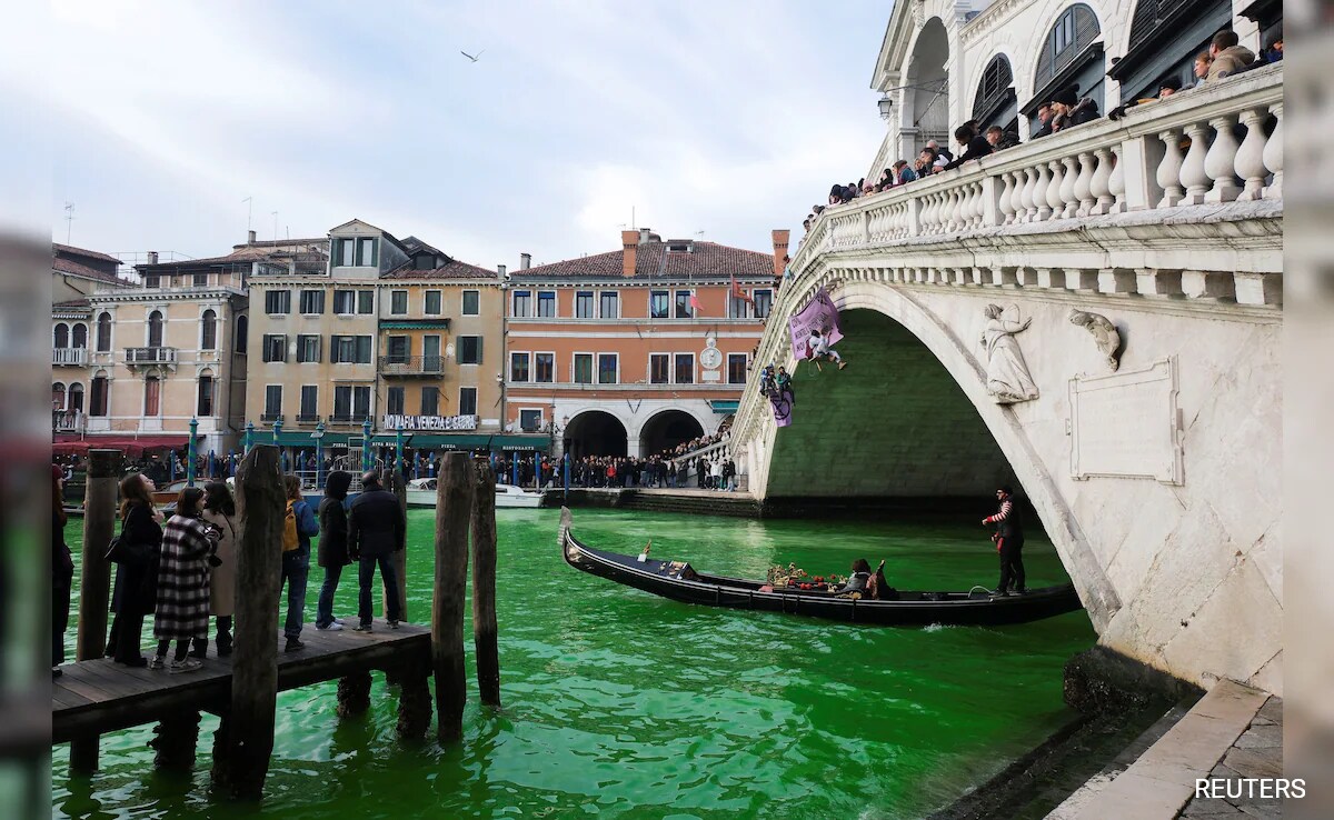 People ride in a boat as waters of Grand Canal turned green after a protest by Extinction Rebellion climate activists in Venice, Italy.