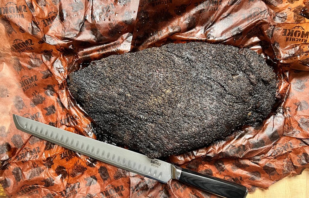 smoked brisket resting on layer of smoke kitchen pink butcher paper