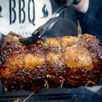 prime rib on a rotisserie being basted with butter and herbs