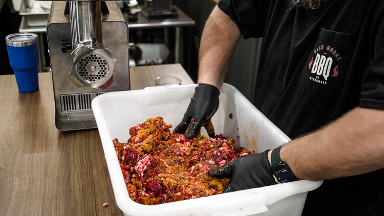 hand mixing seasoning into ground meat