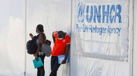 Temporary Refugee Camp in Kara Tepe - Mavrovouni with large white tents having the UNHCR or UNICEF logo and asylum seekers waiting in line for registering, food, beds, clothes etc as seen from the main guarded entrance on 21 September 2020