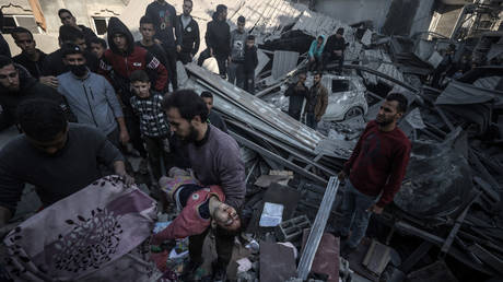 A Palestinian man pulls a child from the rubble after an Israeli airstrike on his Gaza City home