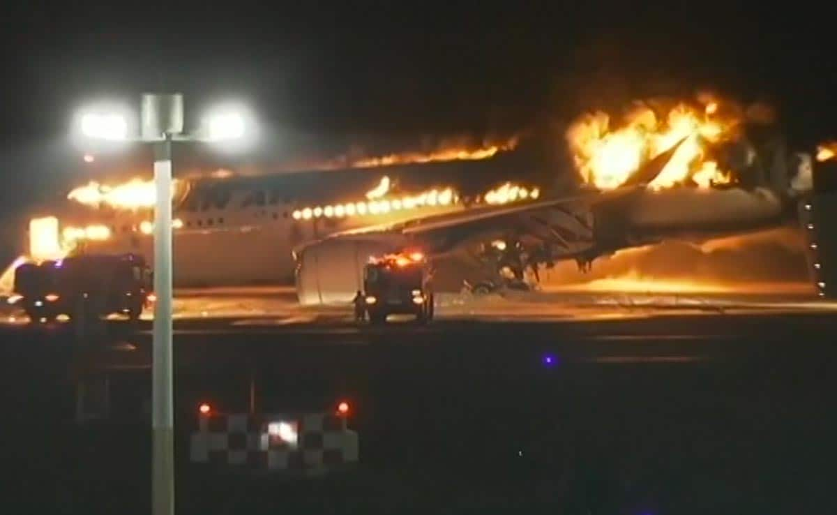 A Japan Airlines plane seen in flames on the runway of Tokyos Haneda Airport