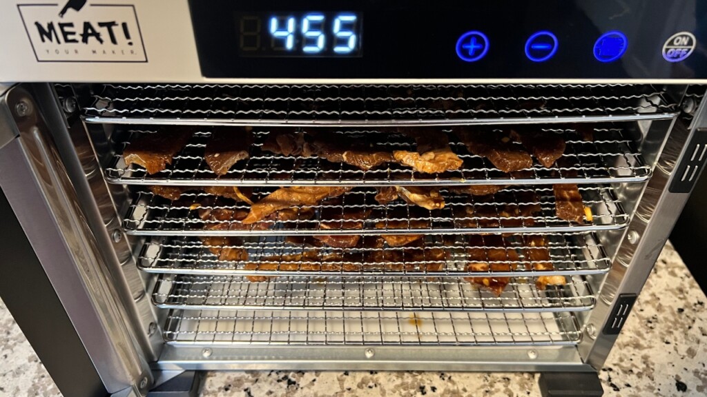 dehydrator on bench filled with beef jerky