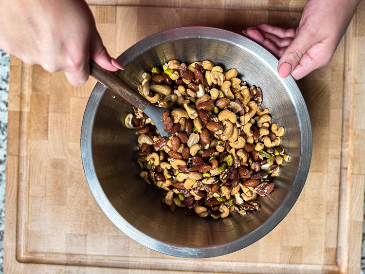 candied nuts being mixed in a metal bowl