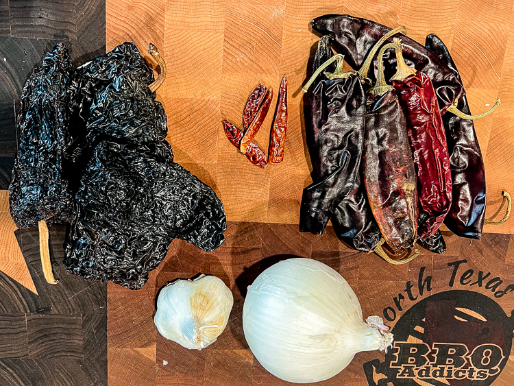 dried chili peppers, onions, garlic on a wooden chopping board