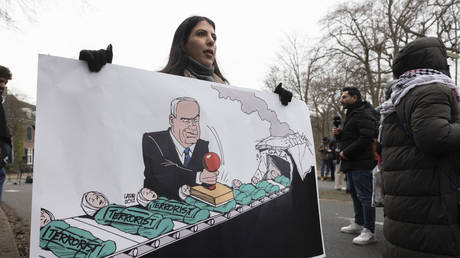 A protester holds up a cartoon of Benjamin Netanyahu outside the ICJ hearing in The Hague