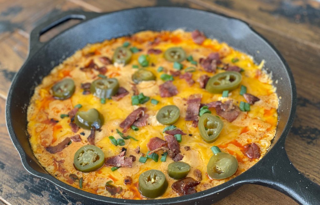 buffalo chicken dip in a skillet with garnishes on top