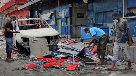 This frame grab taken from AFPTV video footage taken on January 11, 2024 shows people clearing up debris in front of buildings damaged during riots in Port Moresby.