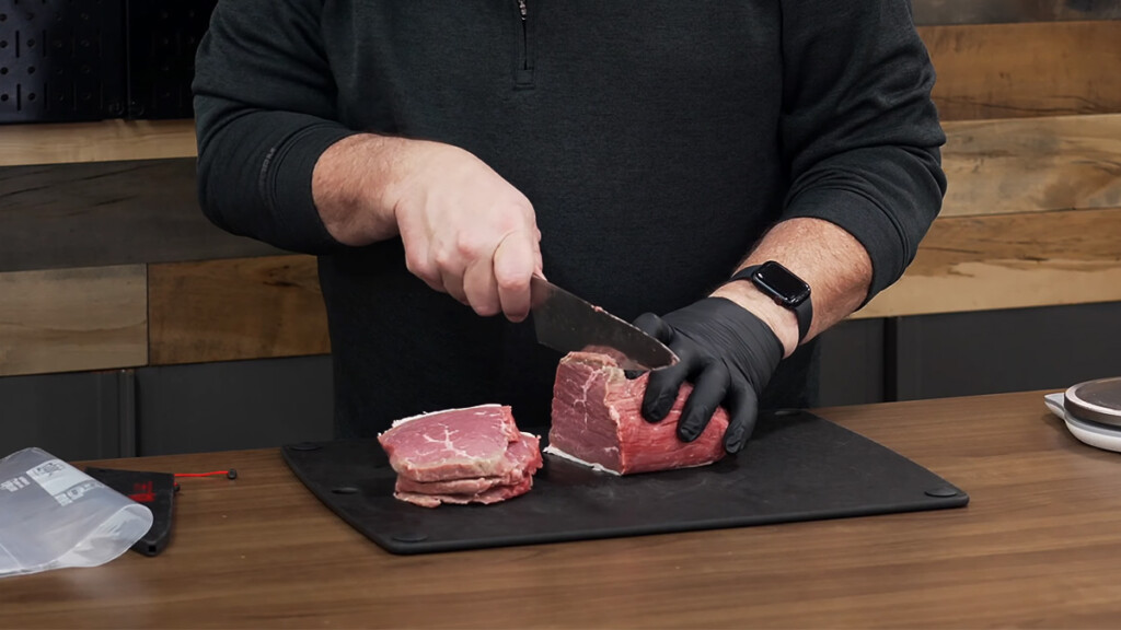 a man slicing beef eye of round for making jerky