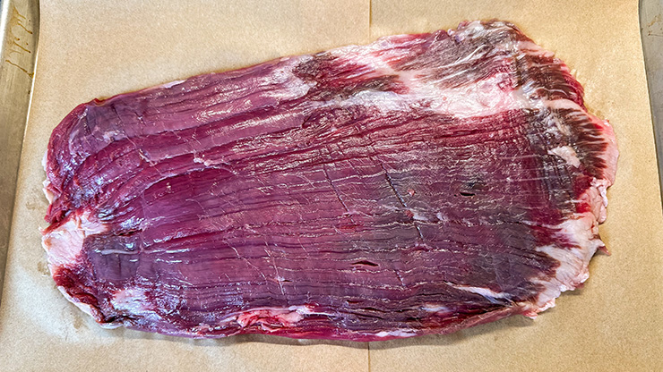 uncooked beef flank steak on a brown paper