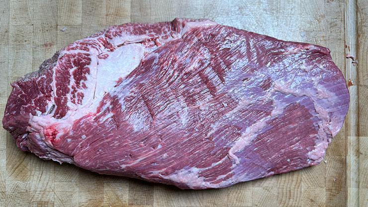 raw beef brisket on a wooden board