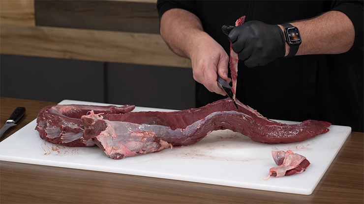 a man trimming venison meat with a knife