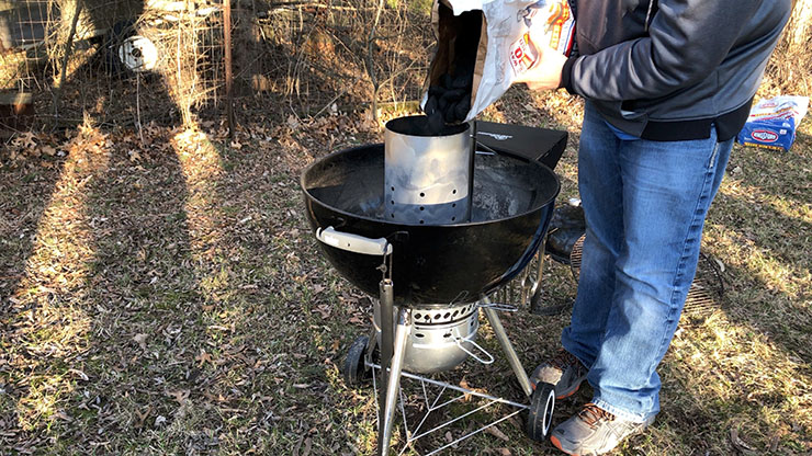 a person dumping charcoal into the chimney starter