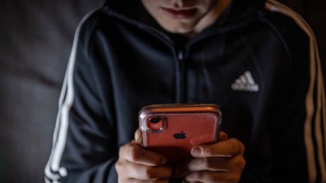 FILE PHOTO: A 12-year-old boy looks at a smartphone screen on March 16, 2023 in Bath, England.