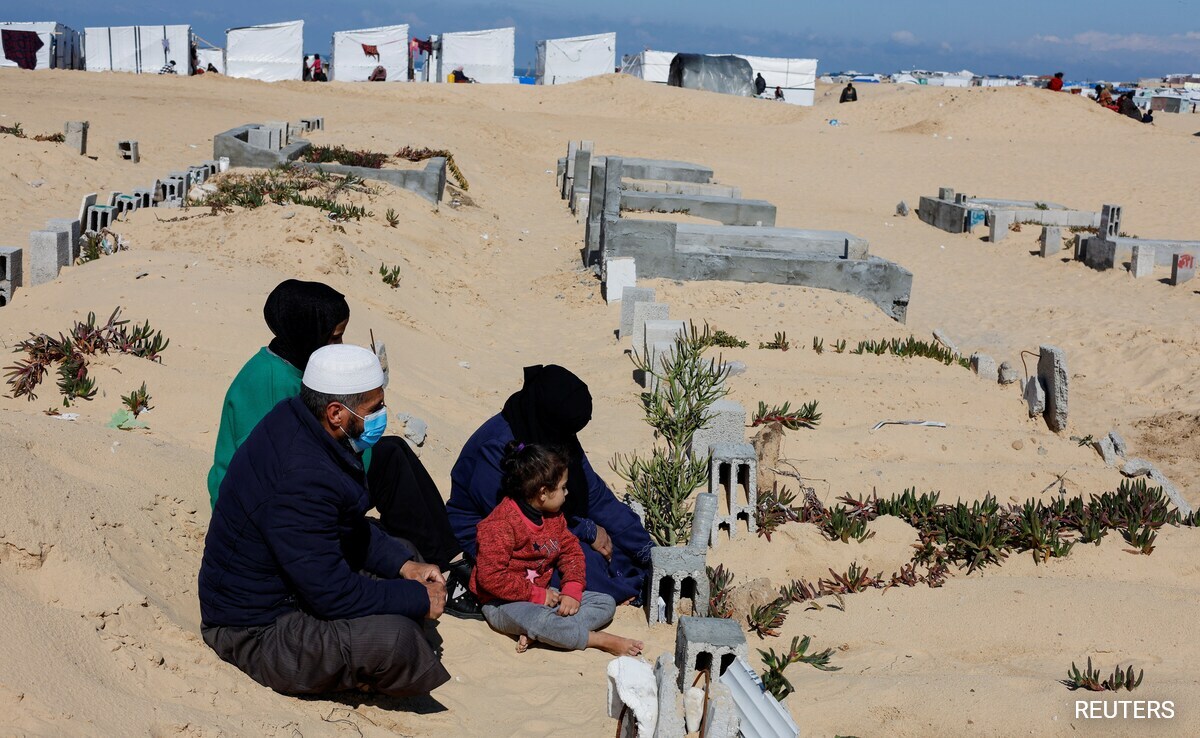 Displaced Palestinians, who fled their houses due to Israeli strikes, shelter in a cemetery, in Rafah in the southern Gaza Strip.